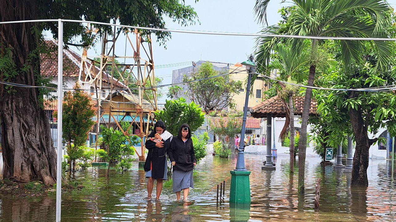 Warga binaan Lapas Perempuan Semarang beraktivitas di tengah banjir. Di belakangnya terlihat perumahan penduduk berlantai dua yang bersebelahan dengan lapas. (baihaqi/jatengtoday.com)