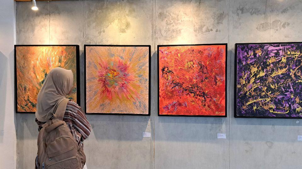 Pengunjung pameran sedang memandang lukisan karya Fiya Ardia. (baihaqi/jatengtoday.com)